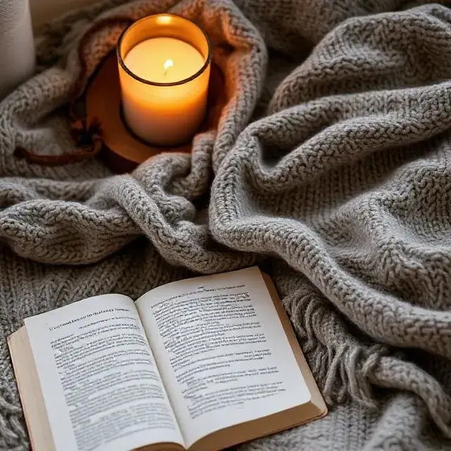 A cozy scene with a blanket, book, and candle.